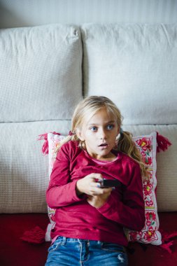 Genç kız Tele önünde uzaktan kumanda ile kanal değiştirme