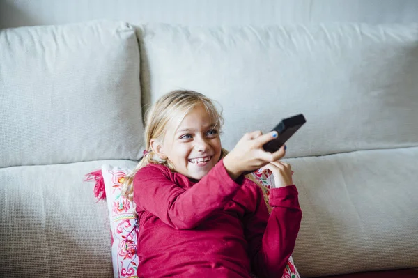 Young Girl Changing Channel With Remote Control In Front Of Tele