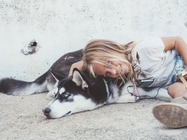 Bella ragazza bionda posa con animale domestico siberiano Husky — Foto Stock