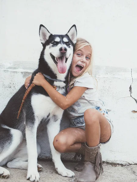 Mooi blond meisje vormt met huisdier Siberische Husky — Stockfoto