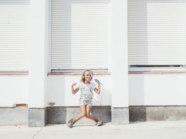 Küçük güzel kız telefonu sahiptir. O kulaklıklar. 