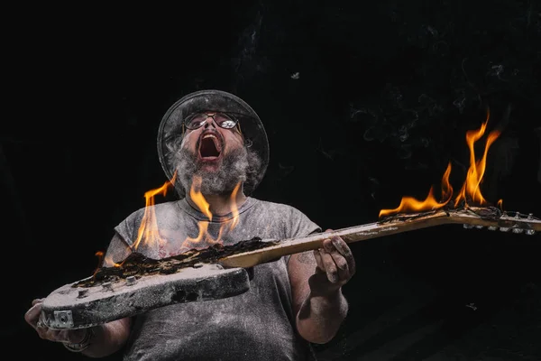 人用吉他与火在白垩和烟尘土之间 — 图库照片
