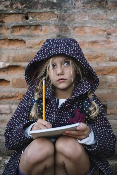 Маленька дівчинка з блокнотом на відкритому повітрі — стокове фото