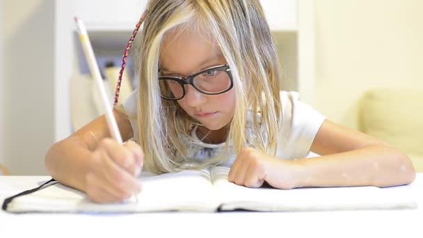 Маленькая девочка пишет в тетрадь — стоковое видео