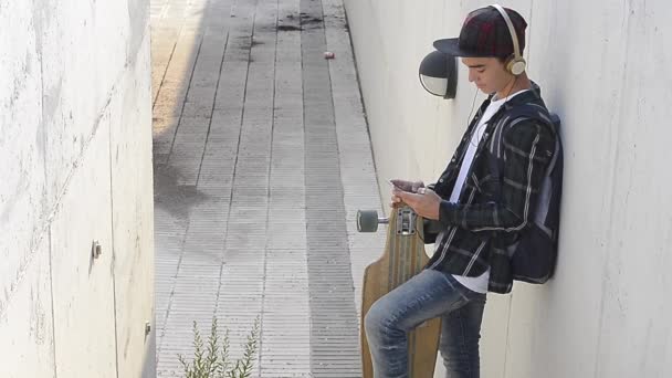 Adolescent dans la rue avec smartphone et écouteurs — Video