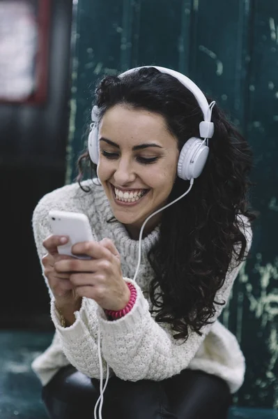 Glad tjej ler han lyssnar på musik med vita hörlurar — Stockfoto