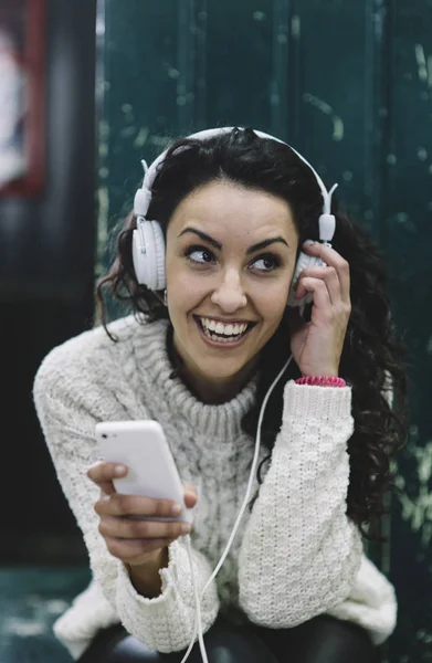 Chica feliz sonriendo él escucha música con auriculares blancos —  Fotos de Stock