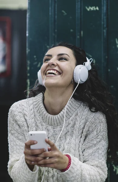 Gadis bahagia tersenyum dia mendengarkan musik dengan earphone putih — Stok Foto