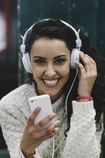 Chica feliz sonriendo él escucha música con auriculares blancos —  Fotos de Stock