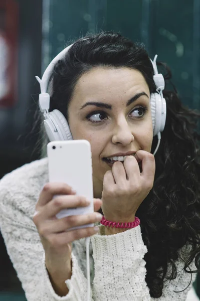 Çekici kız smartphone ve beyaz kulak ile müzik dinlemek — Stok fotoğraf