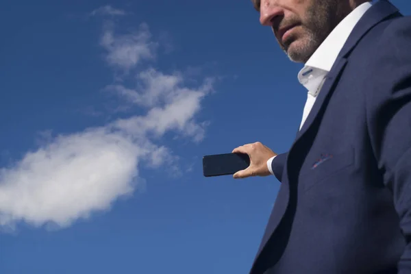 Χέρι που κρατά το smartphone σε φόντο μπλε του ουρανού — Φωτογραφία Αρχείου