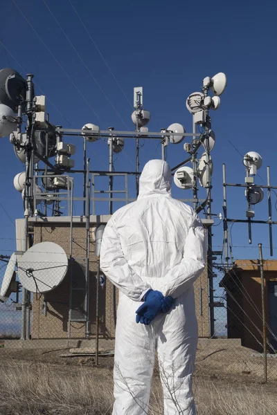 Man die werkt in een wit pak en blauwe handschoenen, antennes — Stockfoto
