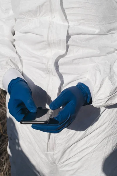 Handen met blauwe handschoenen en smartphone — Stockfoto