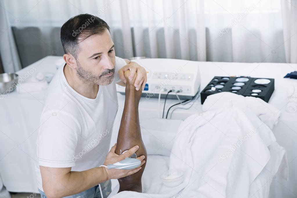 The physiotherapist treating a man using equipment for radio the