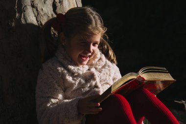 Güzel küçük bir kız parkta bir kitap okuma