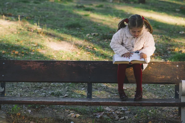 Красива маленька дівчинка читає книгу в парку — стокове фото