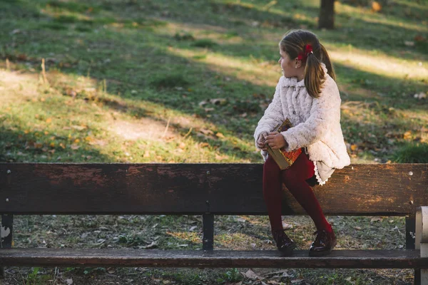 Красивая маленькая девочка читает книгу в парке — стоковое фото