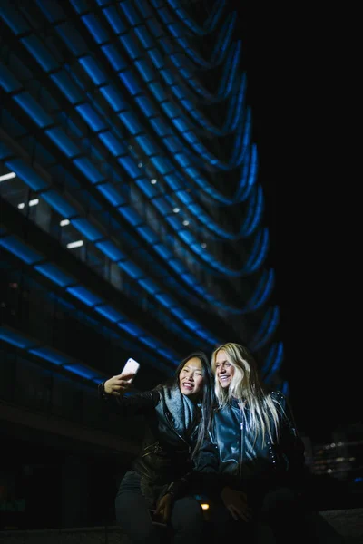 Mulher asiática e mulher loira faz selfie com smartphone . — Fotografia de Stock