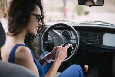 Cep telefonu arabada kullanan güzel genç kadın.