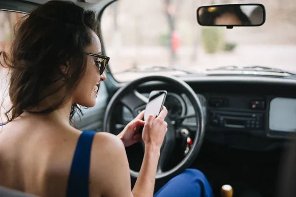 Krásná mladá žena pomocí svého mobilního telefonu v autě. — Stock fotografie