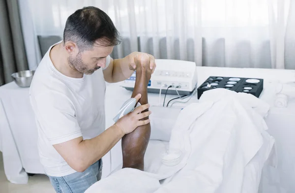 Le physiothérapeute traitant un homme utilisant un équipement pour la radio le — Photo