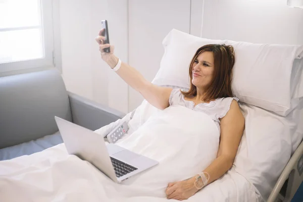 Άρρωστη γυναίκα με Smartphone και laptop στο νοσοκομείο — Φωτογραφία Αρχείου
