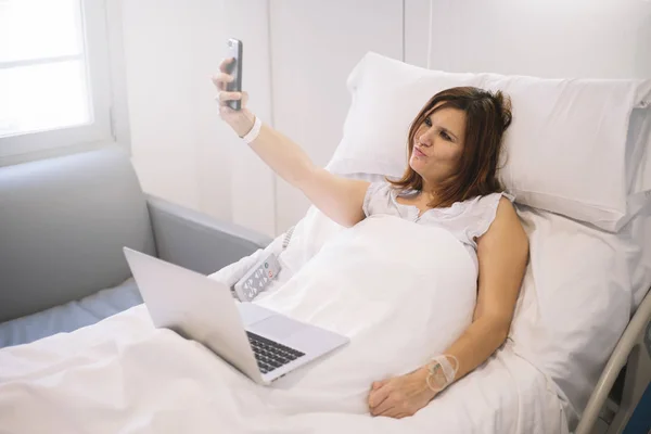 Άρρωστη γυναίκα με Smartphone και laptop στο νοσοκομείο — Φωτογραφία Αρχείου