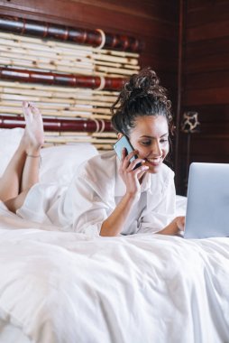 Telefonu ve laptop yatakta güzel kadın