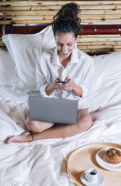 Telefonu ve laptop yatakta güzel kadın