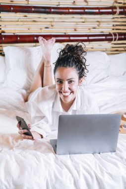 Telefonu ve laptop yatakta güzel kadın