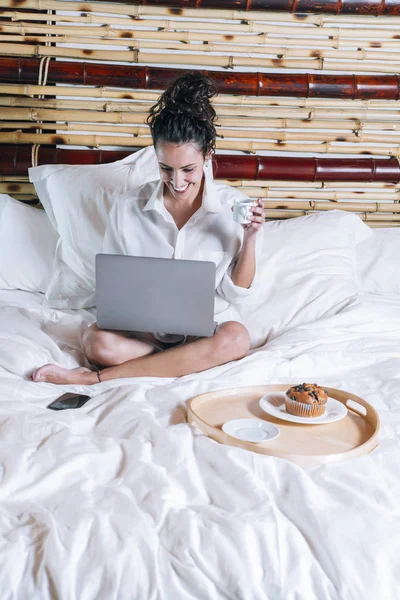 Bella donna con telefono e laptop a letto — Foto Stock