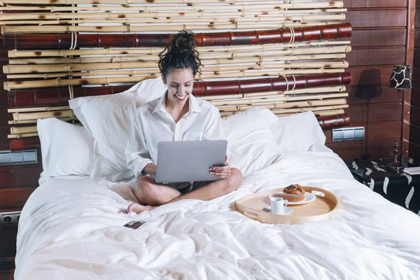 Bella donna con telefono e laptop a letto — Foto Stock