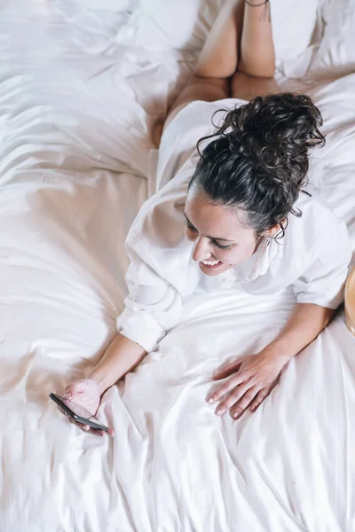 Mujer bonita con teléfono en la cama —  Fotos de Stock