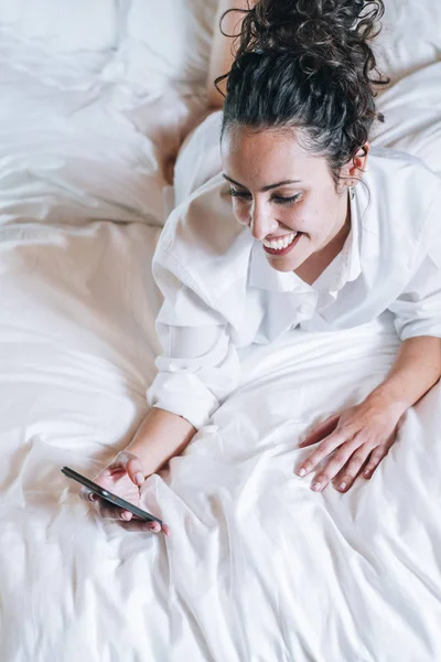 Mujer bonita con teléfono en la cama —  Fotos de Stock