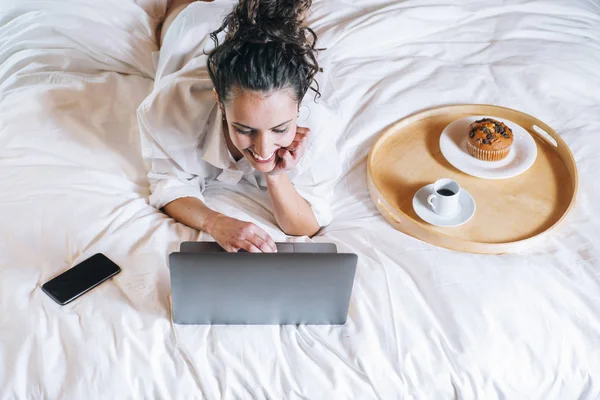 Bella donna con telefono e laptop a letto — Foto Stock