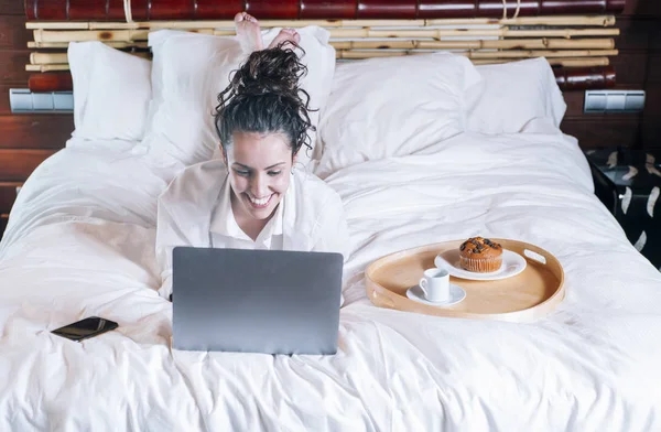 Bella donna con telefono e laptop a letto — Foto Stock