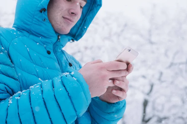 Έφηβο με smartphone και μπλε σακάκι, ημέρα του χιονιού — Φωτογραφία Αρχείου