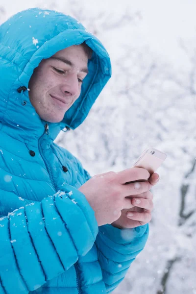 Έφηβο με smartphone και μπλε σακάκι, ημέρα του χιονιού — Φωτογραφία Αρχείου