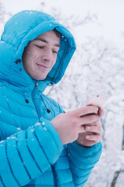 Έφηβο με smartphone και μπλε σακάκι, ημέρα του χιονιού — Φωτογραφία Αρχείου
