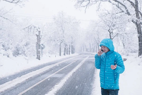 Teenager s smartphone a modrou bundu, den sníh na silnici — Stock fotografie