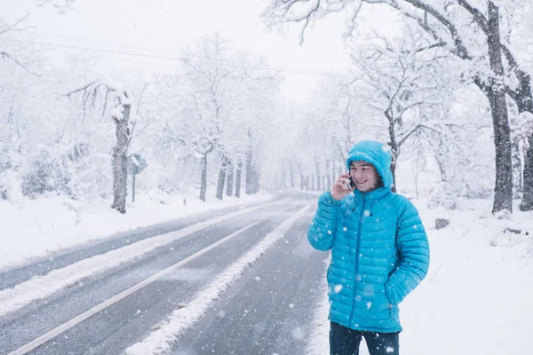 Teenager s smartphone a modrou bundu, den sníh na silnici — Stock fotografie