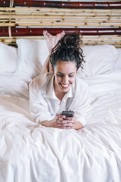 Красивая женщина с телефоном в постели — стоковое фото