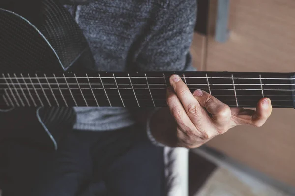 Пожилой человек играет на углеродной гитаре — стоковое фото