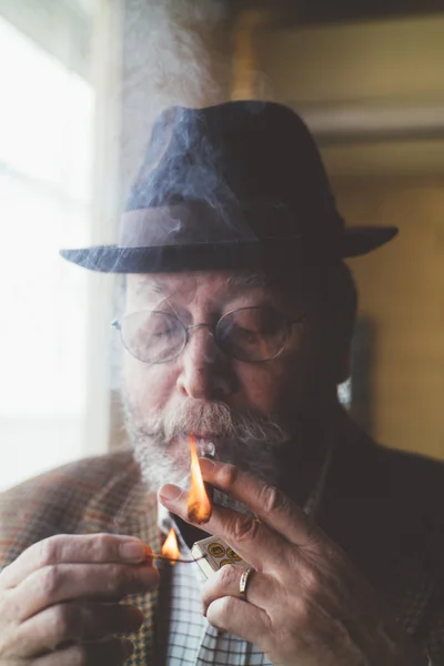 Старший мужчина с дымящейся сигарой — стоковое фото