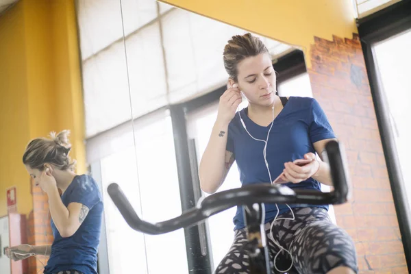Žena cvičí předení v tělocvičně s smartphone — Stock fotografie