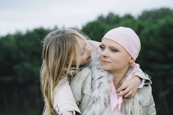 Una mujer con cáncer está al lado de su hija. Una chica se está abrazando — Foto de Stock