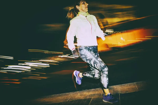 Женщина, практикующая бег по городу ночью — стоковое фото