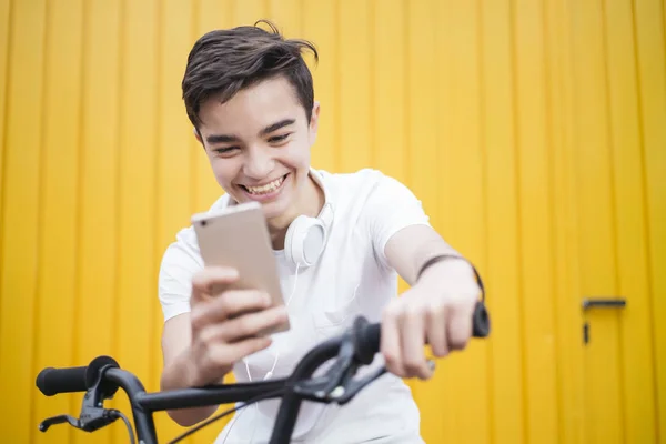 Портрет Красавчика-подростка, улыбающегося, когда он использует свою мобилу — стоковое фото