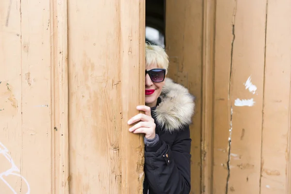 Mulher loira com óculos de sol, atrás da porta — Fotografia de Stock