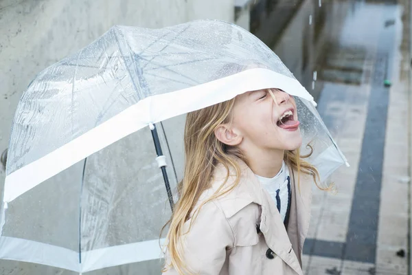Kleines Mädchen mit blauen Augen und großem durchsichtigen Regenschirm. — Stockfoto